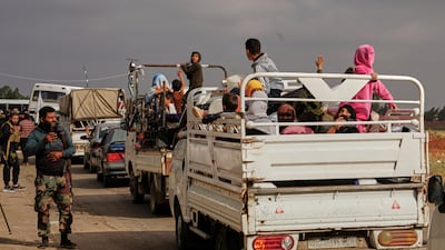 Syrian Bedouin families ride in the back of lorries carrying their belongings, in a convoy led by Red Crescent vehicles. AP