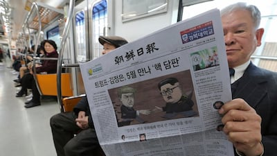 A passenger reads a newspaper with headline of a planned summit meeting between North Korean leader Kim Jong Un and U.S. President Donald Trump. Ahn Young-joon / AP