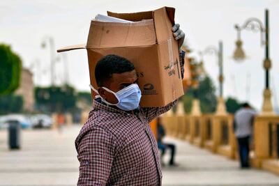 A worker on a Nile cruise ship, wearing a protective face mask, walks carrying a box along the corniche overlooking the river bank in Egypt's southern city of Luxor. AFP