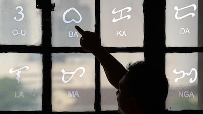 This photo taken on July 15, 2019 shows National Museum researcher Leo Batoon pointing to a Baybayin character etched on a glass window at the National Museum in Manila. From tattoos, shirts, and artworks to a computer font and mobile apps, Baybayin found a rebirth among millennials and professionals learning its 17 characters beyond the marginal mention in history class. - TO GO WITH AFP STORY: Philippines-culture-language, FEATURE by Ayee MACARAIG / AFP / TED ALJIBE / TO GO WITH AFP STORY: Philippines-culture-language, FEATURE by Ayee MACARAIG