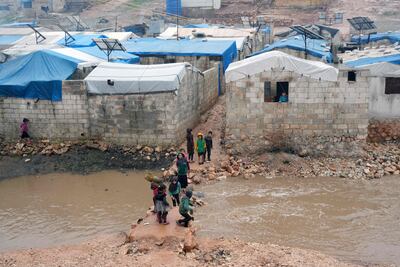 Syrian children cross a stream of water amid heavy rainfall and flooding at a displacement camp near the village of Qah in Syria's northwestern Idlib province. AFP