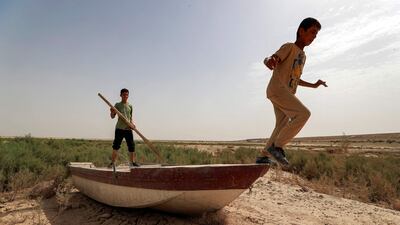 A boy holds an oar while another prepares to jump off a grounded boat on the soil of what was Lake Hamrine in Iraq's Diyala province. All photos AFP