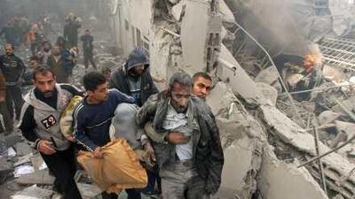 An injured Palestinian prisoner is helped as he and others flee through the rubble of the central security headquarters and prison, known as the Saraya, after it was hit in an Israeli missile strike on Gaza City a year ago today