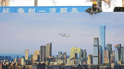 A labourer looks from the top of a wall bearing an image of Beijing’s business district at a construction site. Kim Kyung-Hoon / Reuters