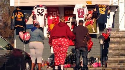 People stand by a small shrine outside the Long Island home of Jovan Belcher.