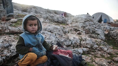A displaced Syrian child from the south of Idlib province holds a piece of bread while sitting out in the open in the countryside west of the town of Dana in the northwestern Syrian region. AFP