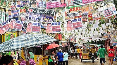 Filipinos walk under election campaign posters as the Philippines goes to the polls this morning. Veejay Villafranca / Getty Images