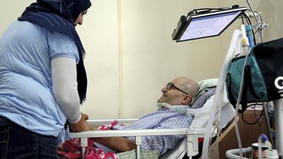 Khaldoun Sinjab is cared for by his wife Yusra Hilal at his home in Sharjah. Satish Kumar for The National