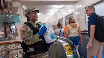 A National Guard soldier offers face masks to commuters at Grand Central Terminal. AFP