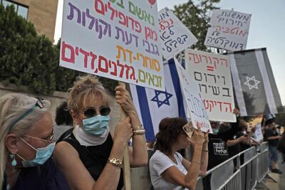 Israeli protesters, wearing protective masks amid the Covid-19 pandemic, carry placards during a demonstration against Prime Minister Benjamin Netanyahu in front of his residence in Jerusalem, on May 17 2020 AFP