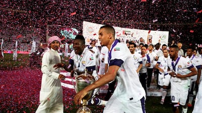 Al Ain’s Asamoah Gyan, left, and Ismail Ahmed, centre, run with the President’s Cup after defeating Al Ahli at Zayed Sports City in Abu Dhabi on Sunday night. Christopher Pike / The National