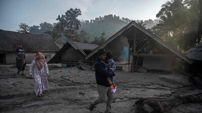 People walk past homes covered with ash and mud. AFP