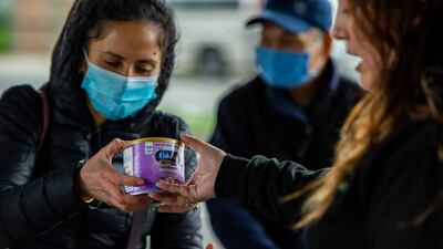 A worker hands over a can of formula to a mother at the food pantry in Massachusetts. AFP