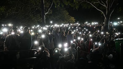 People turn on their mobile phones' torches as they observe a minute's silence for the victims of the Bondi Beach shooting, before the fireworks display in Sydney. AFP