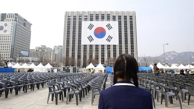 A schoolgirl looks at a giant national flag hanging on a government building. EPA