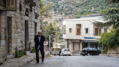 An old man walks past the pharmacy and up Tannourine high street.