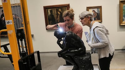 Staff members examine Rodin's 'The Thinker' bronze statue after it was unpacked to install it at the Louvre Museum in Abu Dhabi. Kamran Jebreili / AP photo