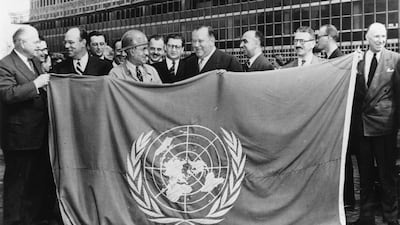 UN Secretary General Trygve Lie, centre, displaying the UN flag in front of the incomplete UN headquarters building in New York, in 1949. Getty Images