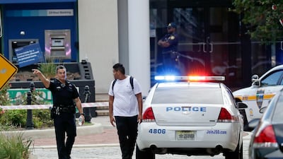 A police officer directs a pedestrian away from a blocked off area near the scene of a mass shooting at Jacksonville Landing. AP Photo
