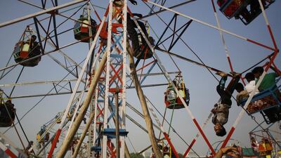 An Indian worker rides upside down to push a giant wheel at a fair ground before the burning of effigies of demon king Ravana during Dussehra celebrations on the outskirts of New Delhi, India. Altaf Qadri / AP Photo