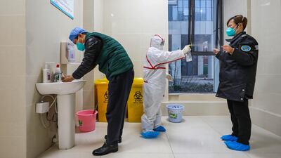 A fully protected worker disinfects the ambulance staff at the emergency center in Wuhan, Hubei province, China. EPA