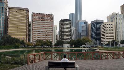 A man sits on a bench in Lake Park during a quiet, overcast day in Abu Dhabi on Tuesday. Delores Johnson / The National