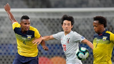 Japan's Shoya Nakajima, centre, vies for the ball with Ecuador's Pedro Pablo Velasco. AFP