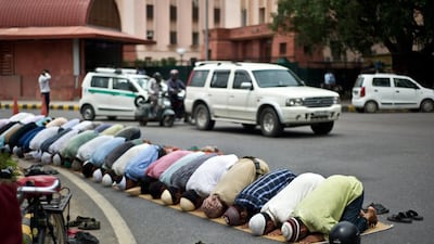 Indian Muslims offer Friday prayers during the holy Islamic month of Ramadan, as traffic drives past in New Delhi on July 19, 2013. Manan Vatsyayana / AFP