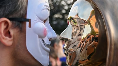 A man wearing a Guy Fawkes mask with the Nakamoto sculpture