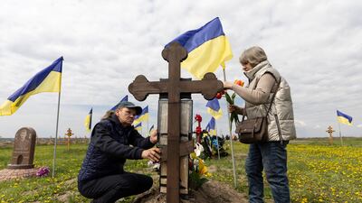 Ukrainian women visit the grave of a relative. Reuters