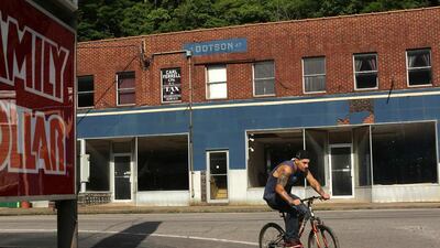 A man rides a bicycle past vacant store fronts in Gilbert, West Virginia. Robert Galbraith / Reuters