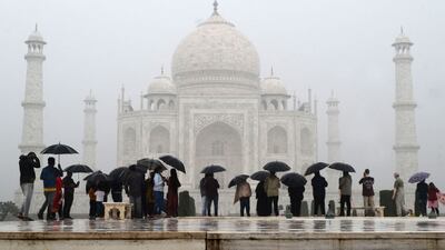 Tourists shelter under umbrellas as they visit the Taj Mahal in Agra, India. AFP