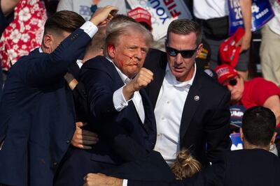 US Republican candidate Donald Trump is seen with blood on his face and surrounded by secret service agents after an assassination attempt on July 13. AFP