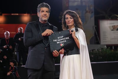 Nabil Ayouch, left, and director Maryam Touzani hold a bag with a 'Stop The Genocide in Gaza' message on the red carpet at the Venice Film Festival. AP