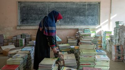 Amanah Nashenas, 45-year-old an Afghan teacher, collects books in a school in Kabul, Afghanistan, on December 22. AP