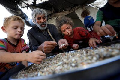 Displaced Palestinians who have not received humanitarian aid pick through leftover food. Reuters
