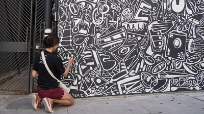 A woman freshens up a mural in downtown Austin.