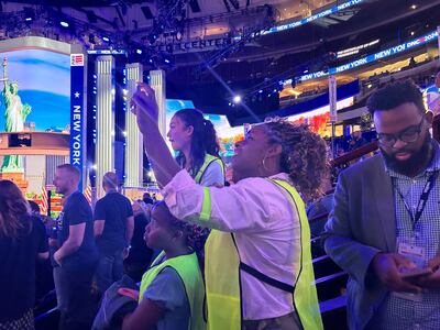 Volunteer Tyra Virden and her daughter Brooklyn watch from the convention floor as state delegations deliver their votes for Kamala Harris to be the Democratic nominee for president. The National