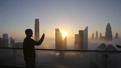 A man takes a photo as the sun rises over the city skyline from a balcony on the 42nd floor of a hotel on a foggy day in Dubai on Saturday. A thick fog shrouded downtown Dubai ahead of a New Year’s Eve fireworks display at the Burj Khalifa. AP Photo / Kamran Jebreili