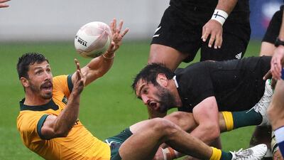 Australia's Jake Gordon passes the ball in the tackle of New Zealand's Sam Whitelock during the Bledisloe Cup rugby game between the All Blacks and the Wallabies in Wellington, New Zealand. AP Photo