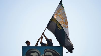 Afghans wave a flag above a portrait of the late Afghan resistance leader Ahmad Shah Massoud in north-eastern Panjshir province, the only region of Afghanistan that has not yet fallen to the Taliban. AFP