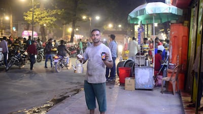 Indian tea seller Vikas Kesharwani, 35, poses with his smartphone at a market in Allahabad. AFP