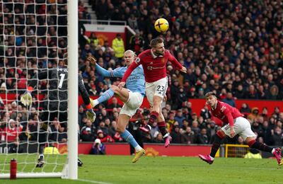 Man United defender Luke Shaw heads the ball clear under pressure from Man City's Erling Haaland. PA