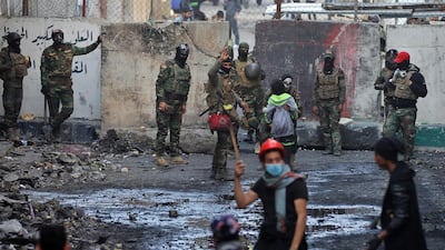 Members of the Iraqi security forces and anti-government protesters gather in front of a concrete barrier. AFP