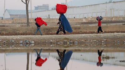 An Afghan woman and her children carry bags on their heads as they walk along a path on the outskirts of Mazar-i-Sharif. Farshad Usyan / AFP