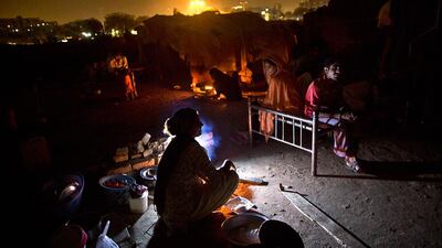 Pakistani women sit outside their makeshift tents baking bread on a fire for their families, in a slum in Islamabad, Pakistan. Muhammed Muheisen / AP Photo