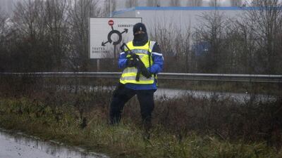 A police officer stands along a road near the industrial area. Yoan Valat / EPA