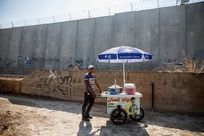 Twenty-two-year-old Islam Daoud stands with his lemonade stand nearby Israel's 8 meter high separation barrier in the Palestinian city of Qalqilya Heidi Levine for The National