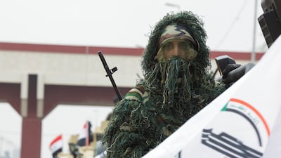 In Baghdad, a member of Iraq's Popular Mobilisation Forces rides in a military vehicle next to a flag during a parade marking the eighth anniversary of defeating ISIS in 2017. Reuters
