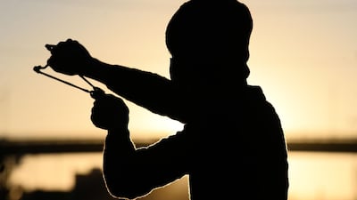 A demonstrator uses a slingshot to hurl stones at security forces during ongoing anti-governments protests in Najaf. AFP